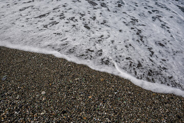 oceano de agua salada con olas, piedras y arena