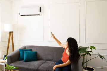 Happy woman at home turning on the air conditioner