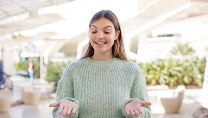 young pretty woman holding an object with both hands on copy space, showing, offering or advertising an object