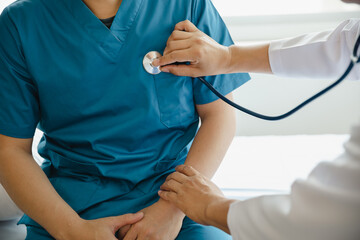 Closeup of male doctor using stethoscope making heart beat with patient in examining room at hospital. Medical checkup. Medical and healthcare.
