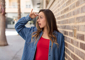 pretty woman looking bewildered and astonished, with hand over forehead looking far away, watching or searching