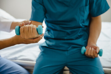 Doctor or Physiotherapist working examining treating injured arm of athlete male patient, stretching and exercise, Doing the Rehabilitation therapy pain in clinic.