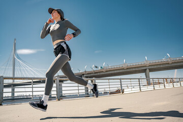 Spectacular foreshortening of a woman running fast in sportswear, cardio training.