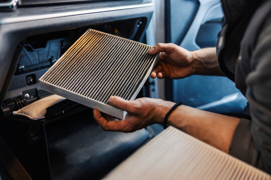 Hands of a mechanic taking out dirty and old air filter in car at mechanic's shop.