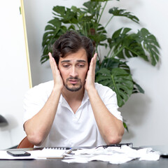 Close up of unhappy man sitting at the table, stressed and confused by calculate expense from...