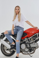 Naklejka na ściany i meble Studio shot of isolated in white background female biker with red colored motorcycle.