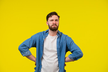 Photo of doubtful unsure man wear turquoise clothes comparing arms empty space isolated yellow color background