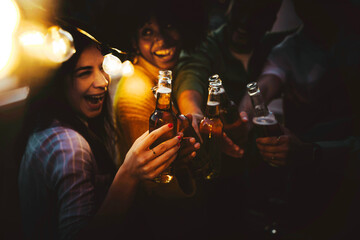 Happy friends enjoying night party on rooftop terrace - Group of multiracial young people drinking...