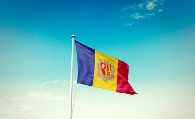 Waving Flag of Andorra in Blue Sky. The symbol of the state on wavy cotton fabric.