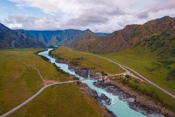 Landscape suspension Oroktoysky bridge over Katun river in valley of Altai Mountains, aerial top view. Popular landmark in Chemal Siberia, Russia