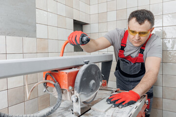 Tile cutting tile on wet saw machine. Work tiler with cut ceramic