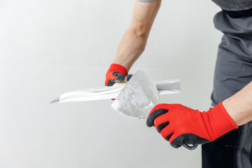 Master builder applies white plaster on spatula. Repair of apartment, leveling walls with putty
