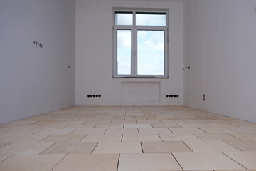Renovation in a new building. Room with window in perspective. Stage of laying floor. Plywood floor...