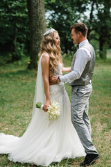 Amazing smiling wedding couple. Pretty bride and stylish groom. Romantic wedding moment, newlyweds in nature in the park.