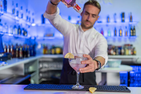 Barman preparing cocktail in glass with orange slice