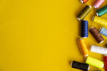 Spools of sewing thread with assorted colors on a yellow background.