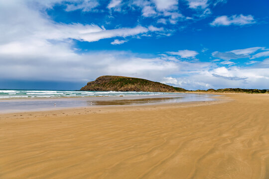 wide sandy beach in canibal bay with a mountain in the background, Otago region, New Zealand