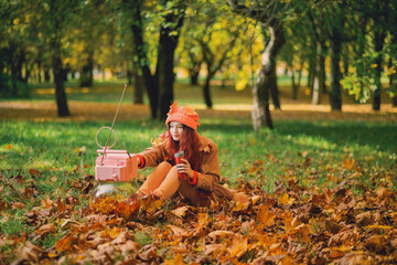Redhaired young hipster woman watching retro TV in the park in the fall. Recreation Concept