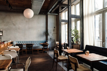 Spacious bright interior in cafe with chairs and concrete walls and wooden floor indoors - 602975973