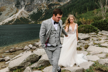The bride and groom near the lake in the mountains. Newlyweds together against the backdrop of a...