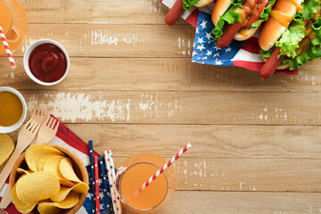 4th of July American Independence Day traditional picnic food. Hot dog with potato chips and cocktail, American flags and symbols of  USA Patriotic picnic holiday on wooden background. Top view.