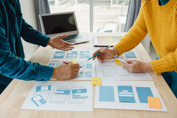 Close up ux developer and ui designer brainstorming about mobile app interface wireframe design on...