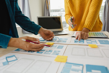 Close up ux developer and ui designer brainstorming about mobile app interface wireframe design on...