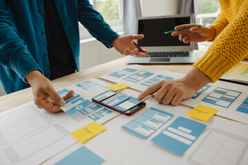 Close up ux developer and ui designer brainstorming about mobile app interface wireframe design on...