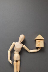 wooden man holding a house made of cubes
