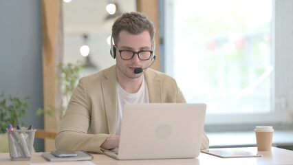 Young Businessman with Headset Talking with Customers Online in Call Center