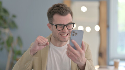 Portrait of Young Businessman Celebrating Success on Smartphone