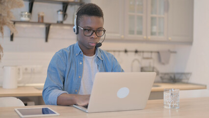 Young African Man with Headset Working on Laptop