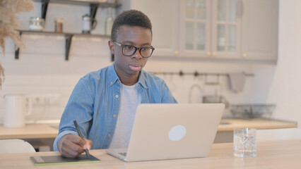 Young African Man Working on Laptop and Graphic Tablet, Designing