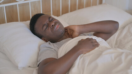 Fototapeta na wymiar Tired Young African Man with neck Pain Sleeping in Bed