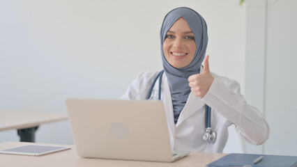 Fototapeta na wymiar Thumbs Up by Muslim Female Doctor on Laptop in Clinic