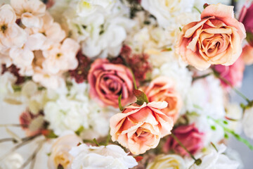 Background of white, cream, pink roses and other flowers as part of a festive decoration, selective soft focus.