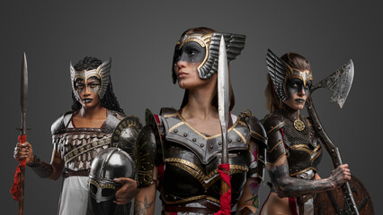 Shot of ancient three warriors women dressed in armour against gray background.