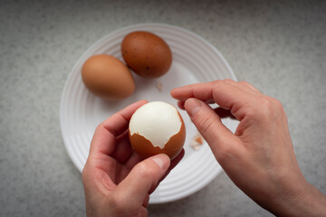 Caucasian female peeling hard boiled eggs closeup view from above