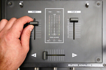 hand on dj mixer crossfader (detail closeup) analog music equipment, super macro, knobs and volume adjusters