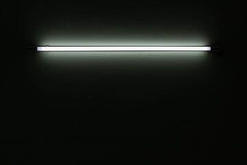 White neon light bulb on white wall.