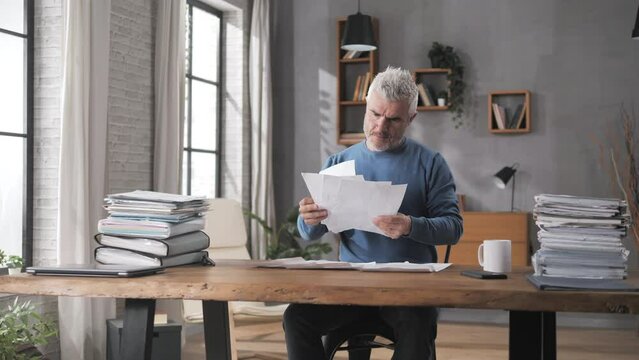 financial issue concerned man looks at tax bills gets upset,bank loan,frustrated person at the desk looking at the account statement expenses gets angry