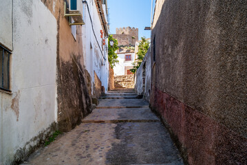 Fototapeta na wymiar Callejuela ascendente de un barrio medieval, con castillo al fondo.