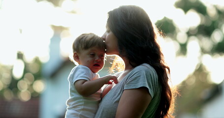 Candid mother kissing baby outside