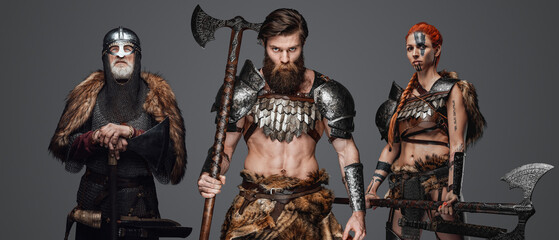 Studio shot of nordic warriors with armour and axes looking at camera together.