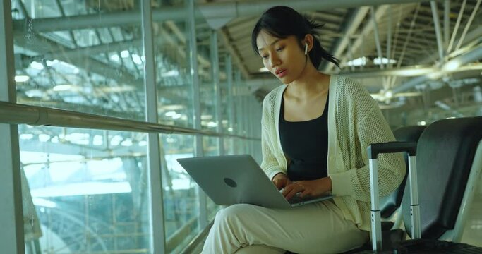 Young woman using laptop for video call in airport. She using laptop to work in outside.