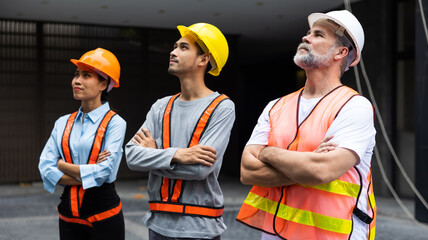 Arms crossed. Unity and teamwork concept. Architect contractor senior man and team engineering standing together in construction site. Professional civil engineer team