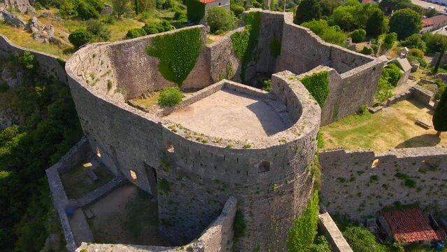 This aerial stock video captures the stunning ruins of the Old Bar or Stari Bar, a historical landmark in Montenegro. The drone footage showcases a bird's eye view of a stone fortress and an aqueduct