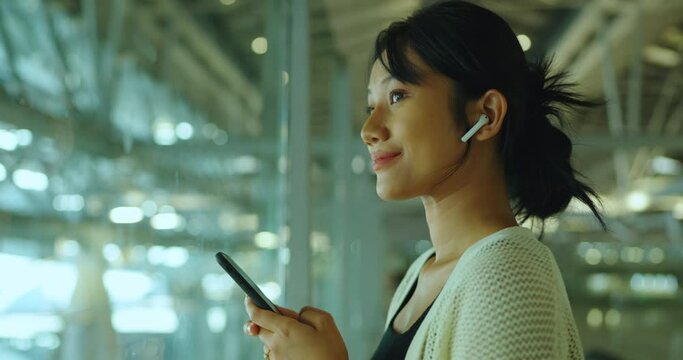 Beautiful woman wearing earphones and smile. She listin music in smartphone. Lifestyle and Technology concept.