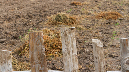 Plot of freshly plowed land next to a brown fence