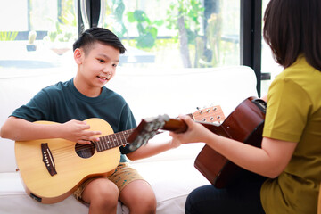 Education concept, learning music. Mother and son playing music together at home. Music teacher...